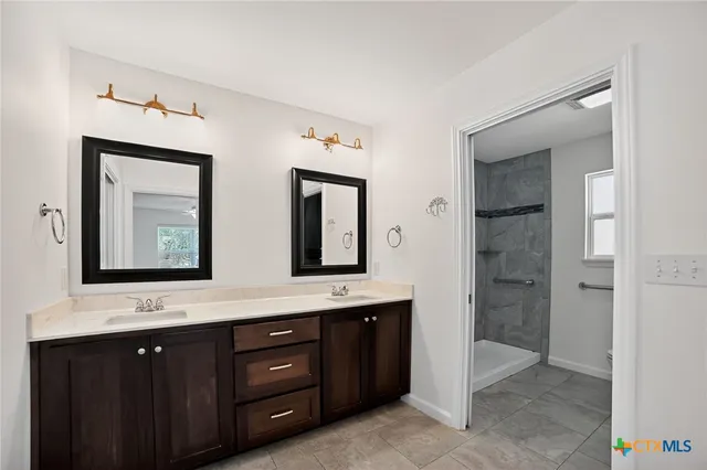 a bathroom with a double vanity sink a large mirror and a bathtub