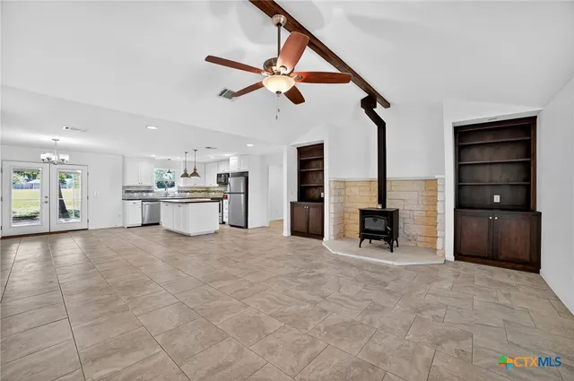 a view of an empty room with cabinet and windows