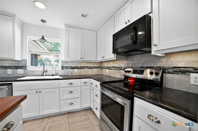 a kitchen with white cabinets and black appliances