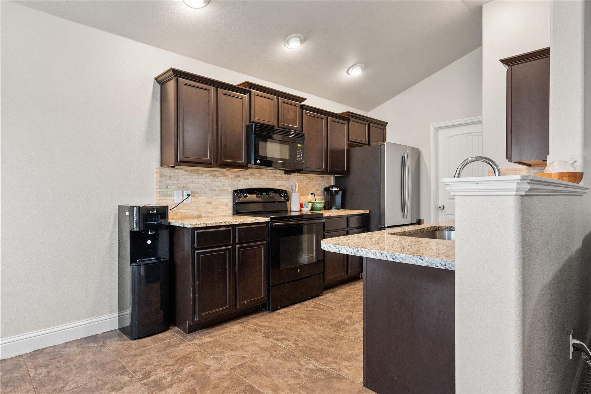 7026 97th Street Lubbock, TX 79424 - Photo 13 of 30 a kitchen with stainless steel appliances granite countertop a refrigerator stove top oven and sink