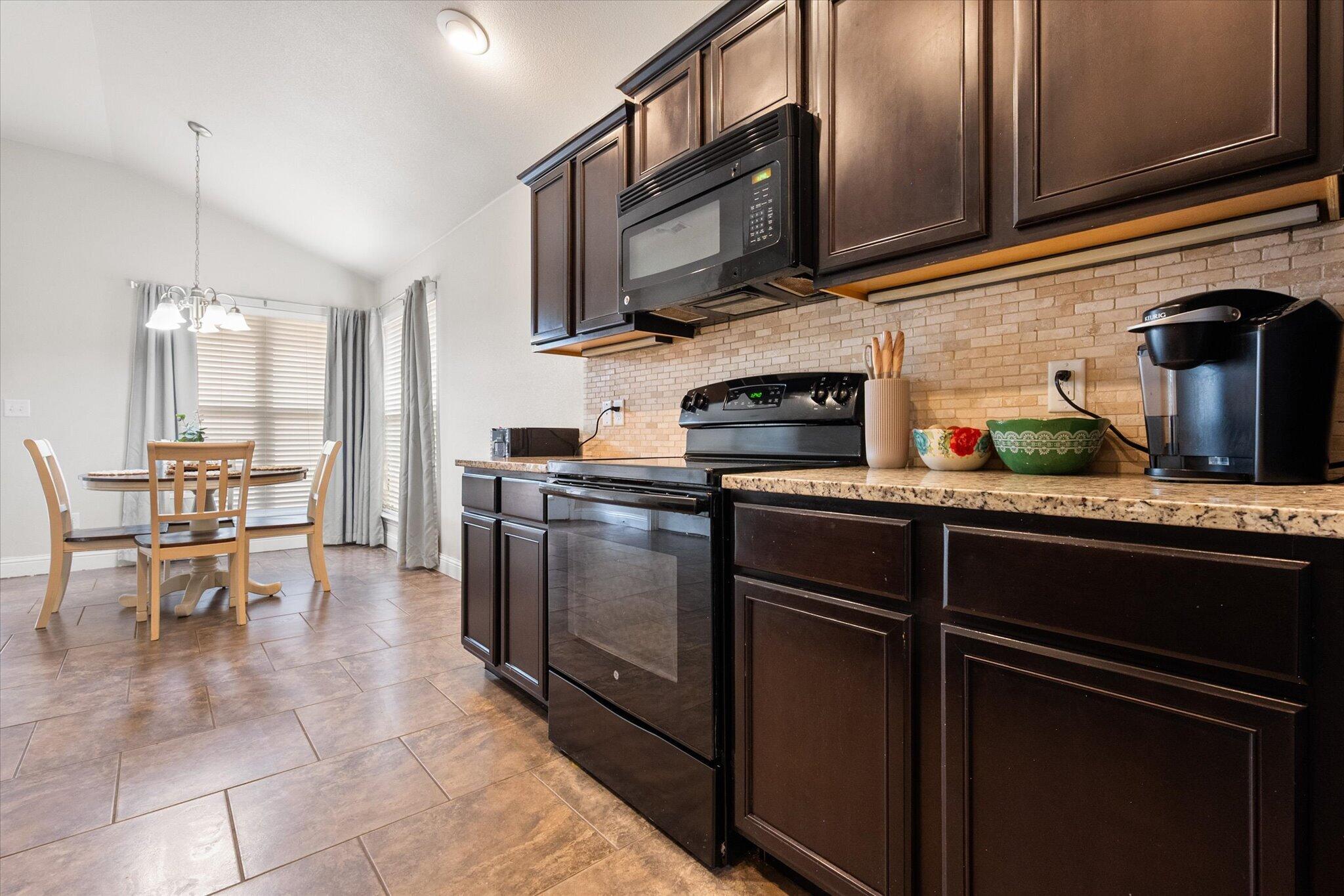 7026 97th Street Lubbock, TX 79424 - Photo 15 of 30 a kitchen with stainless steel appliances granite countertop a refrigerator and a stove top oven
