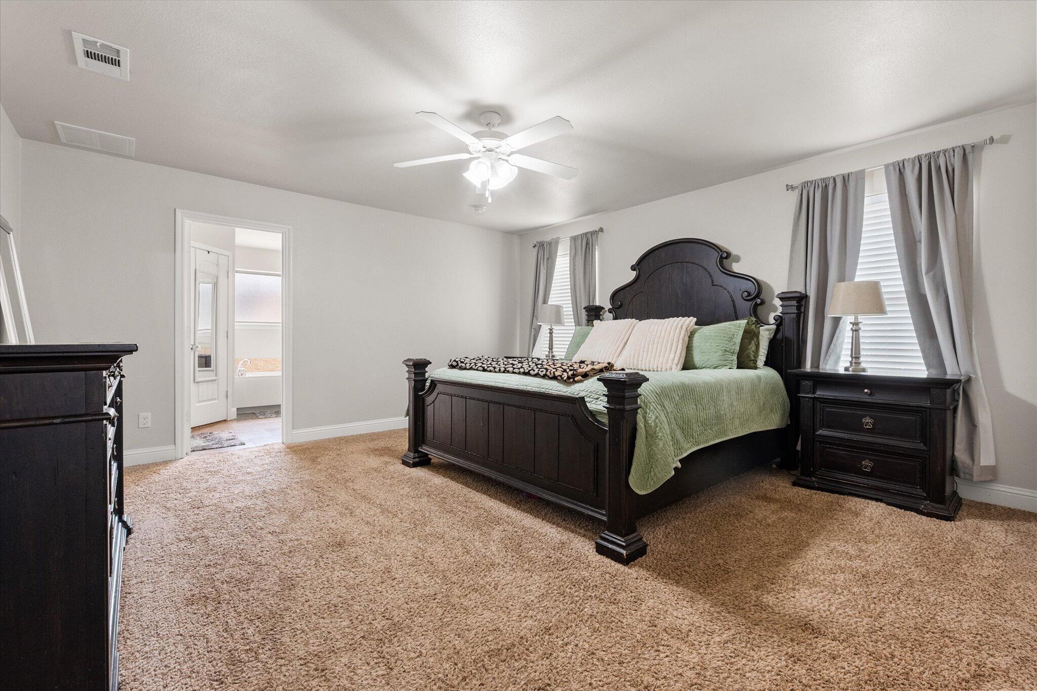 7026 97th Street Lubbock, TX 79424 - Photo 21 of 30 a bedroom with a bed and a chandelier