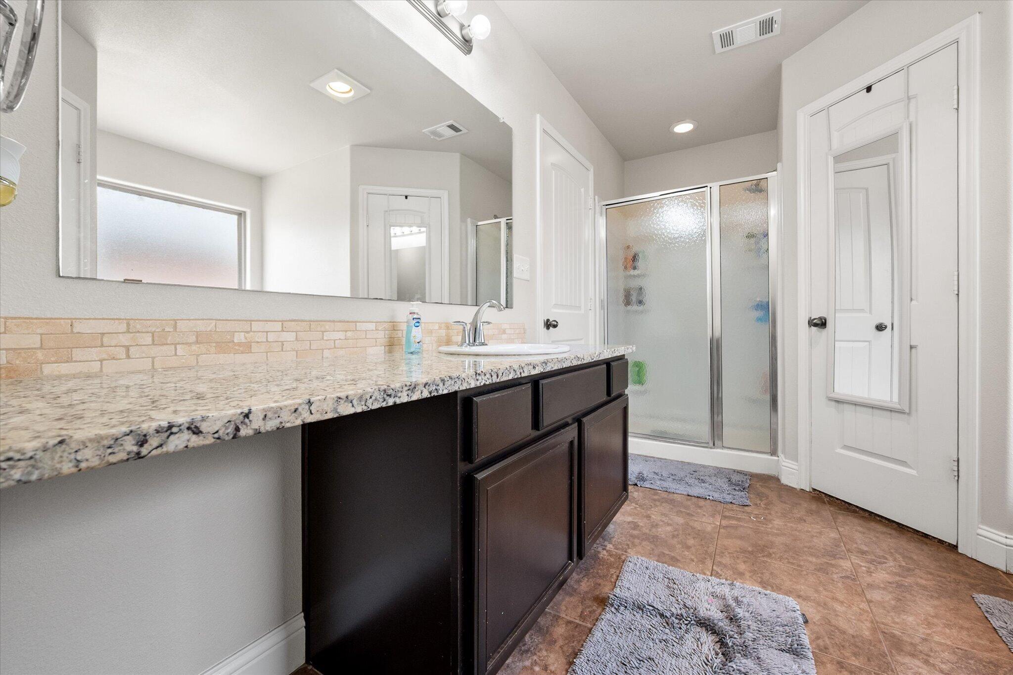 7026 97th Street Lubbock, TX 79424 - Photo 27 of 30 a bathroom with a granite countertop sink and a mirror