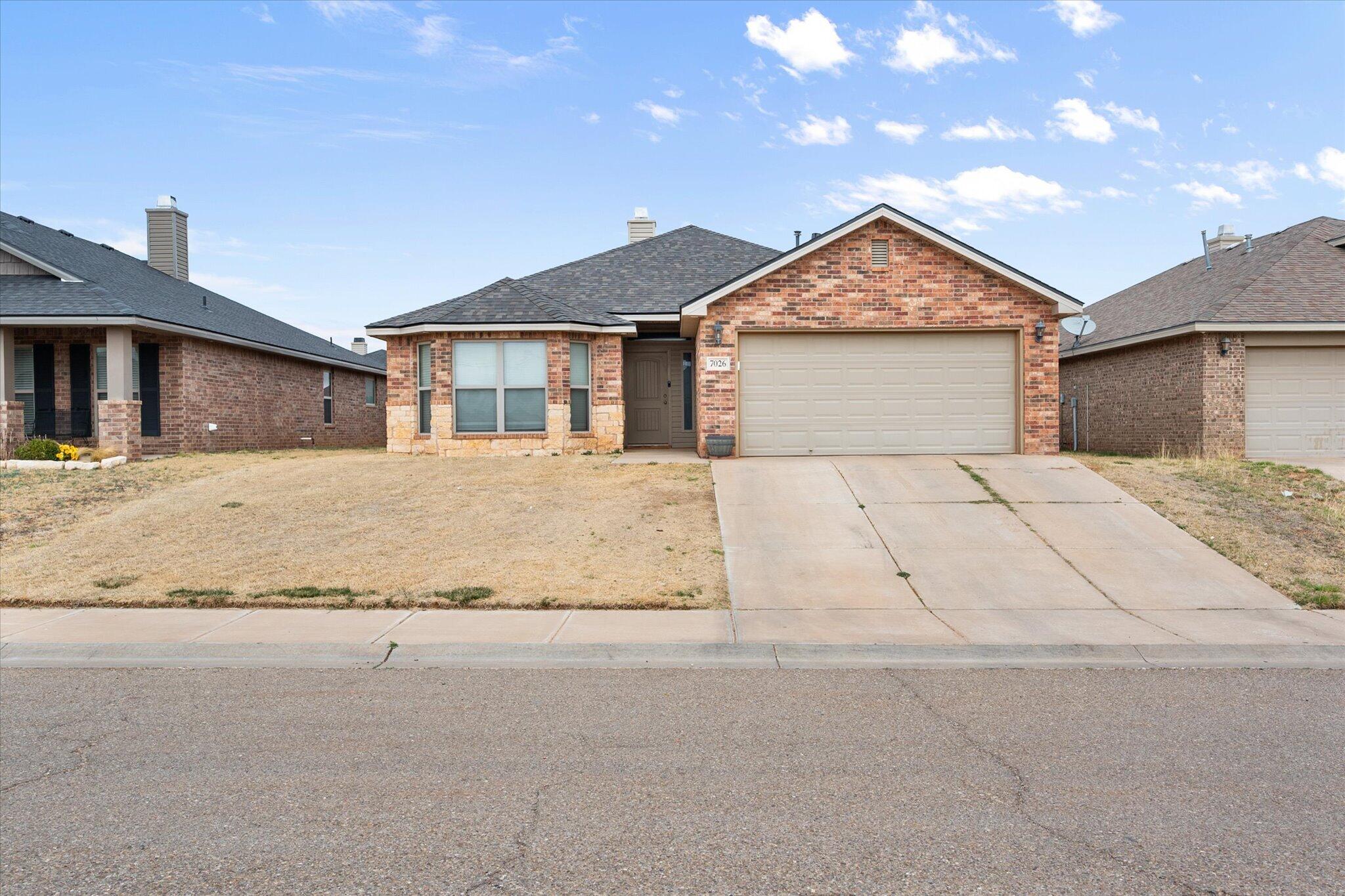 7026 97th Street Lubbock, TX 79424 - Photo 3 of 30 a front view of a house with a yard and garage