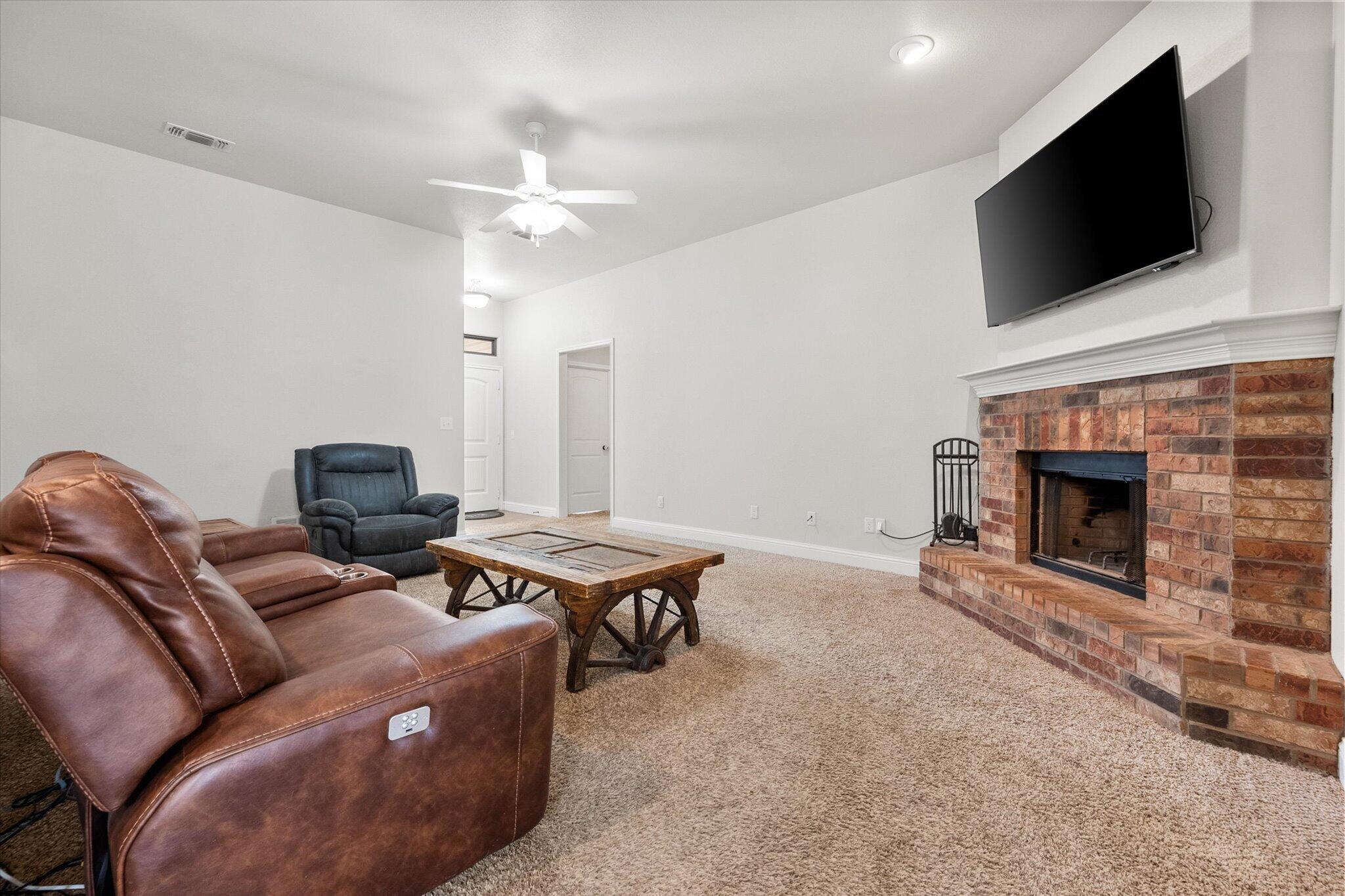 7026 97th Street Lubbock, TX 79424 - Photo 6 of 30 a living room with furniture a flat screen tv and a fireplace