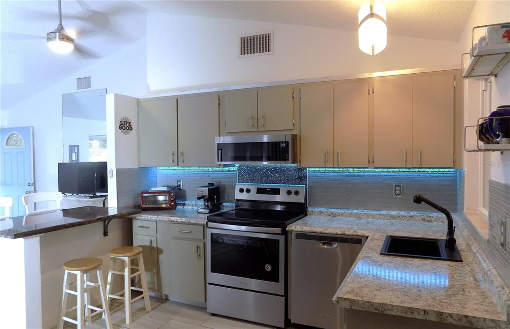 7344 Como Drive New Port Richey, FL 34655 - Photo 13 of 34 a kitchen with stainless steel appliances granite countertop a sink stove and refrigerator