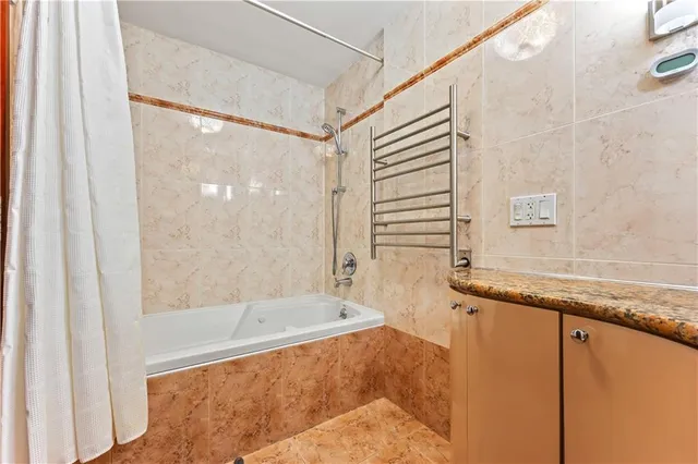 a bathroom with a granite countertop bathtub and shower