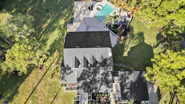 an aerial view of a house with a yard and large trees