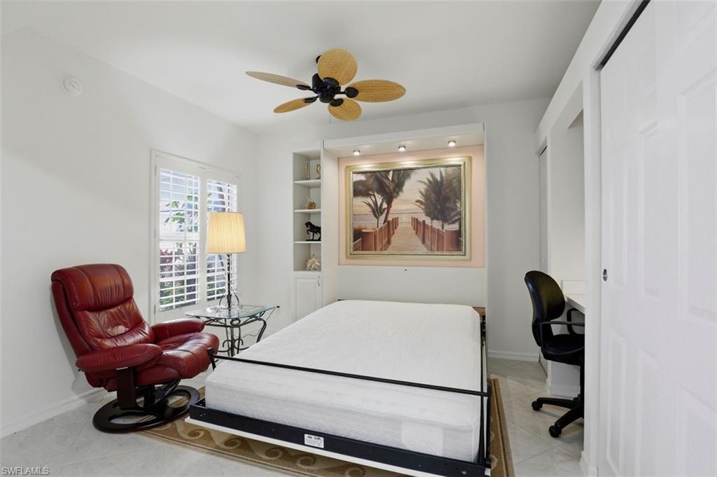 23820 San Marino Road, Unit 102 Estero, FL 34135 - Photo 23 of 28 Bedroom featuring ceiling fan, a desk, a closet, and light tile patterned flooring