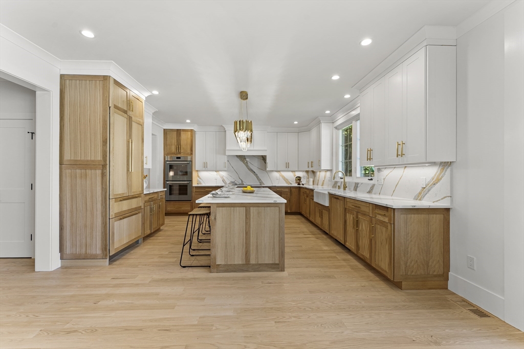 59 Henderson Street Needham, MA 02492 - Photo 6 of 32 a large kitchen with stainless steel appliances a large counter top a stove a refrigerator and white cabinets