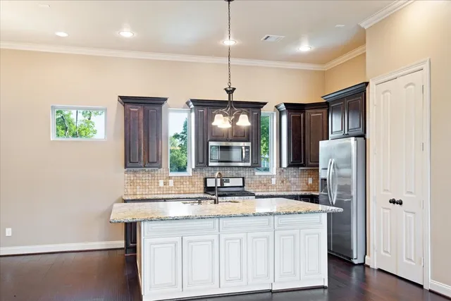 a kitchen with stainless steel appliances granite countertop a refrigerator a sink dishwasher a oven and a dining table with wooden floor