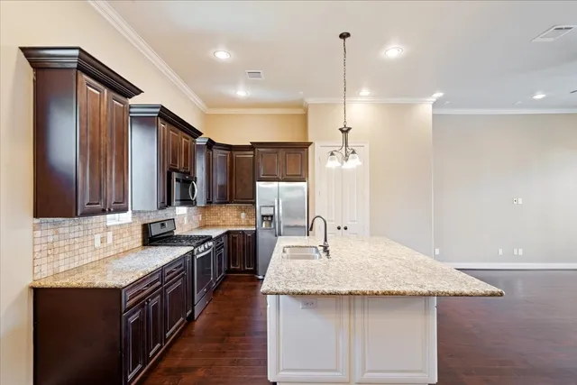a kitchen with kitchen island granite countertop a sink and a refrigerator