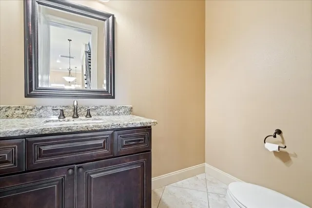 a bathroom with a granite countertop sink vanity mirror and toilet