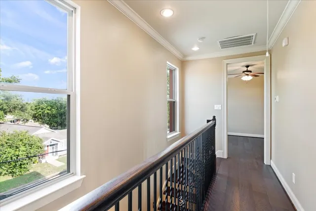 a view of a hallway with wooden floor and a bathroom