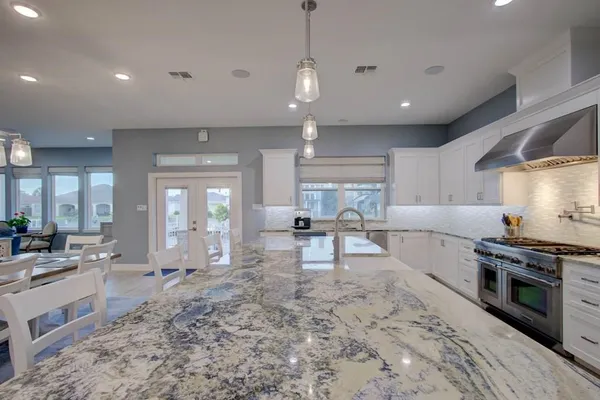 a large kitchen with kitchen island a stove a sink a dining table and chairs