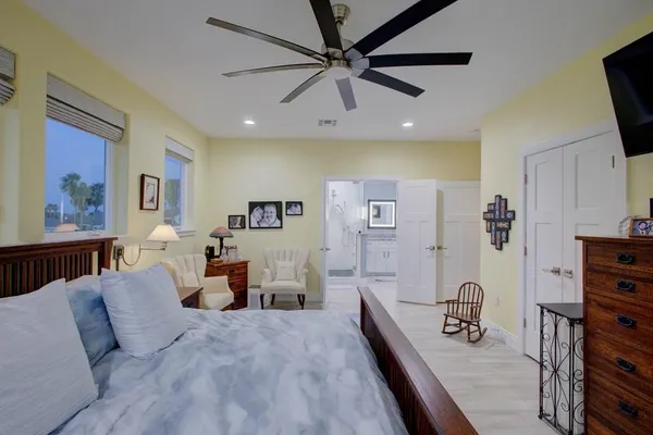a spacious bedroom with a bed a dresser and a flat screen tv