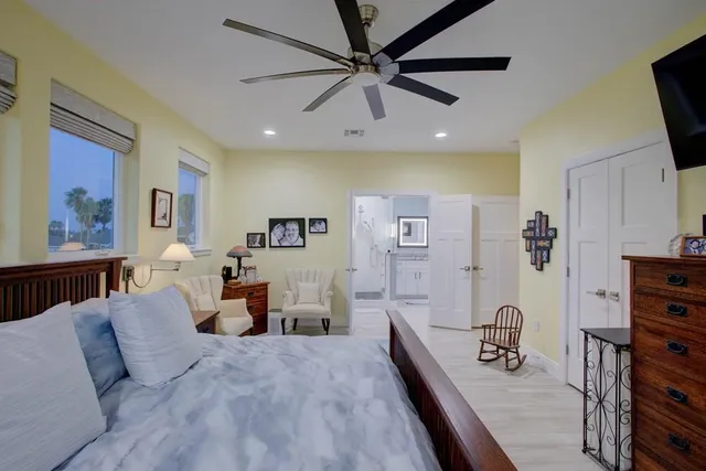 a spacious bedroom with a bed a dresser and a flat screen tv