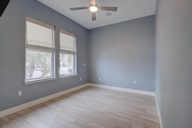 an empty room with wooden floor and windows