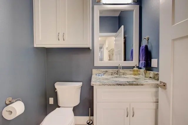 a bathroom with a granite countertop toilet sink and mirror