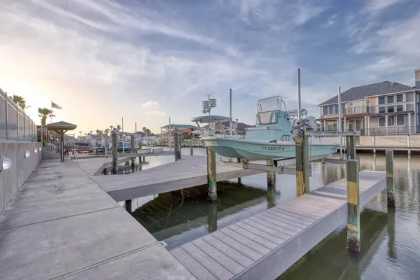 a view of a roof deck with table and chairs a barbeque with wooden floor and fence