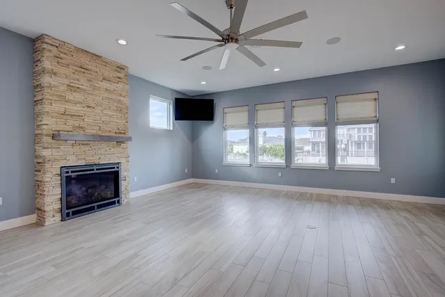 an empty room with windows fireplace and a ceiling fan