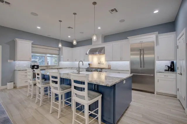 a kitchen with cabinets a sink dishwasher a island and chairs in it