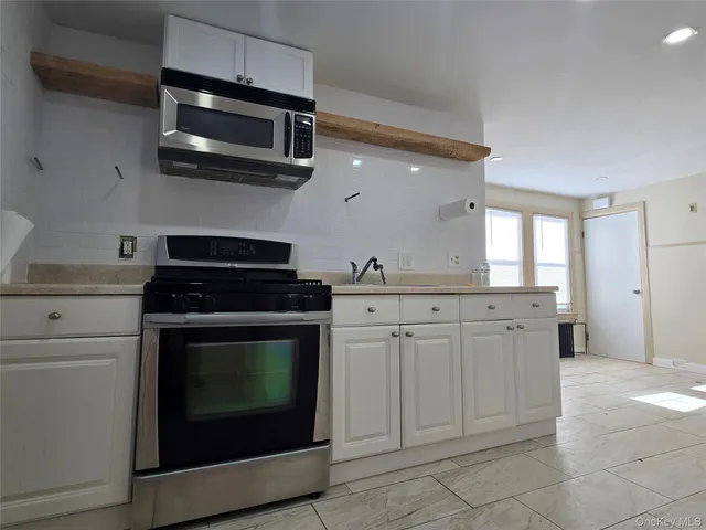 a kitchen with stainless steel appliances granite countertop a stove microwave and cabinets
