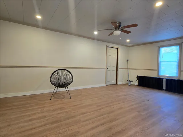a view of an empty room with a window and wooden floor