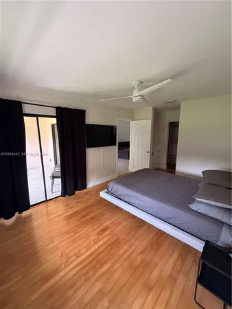 a bedroom with a bed and a dresser with wooden floor