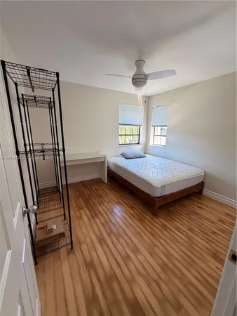 a bedroom with wooden floor and window