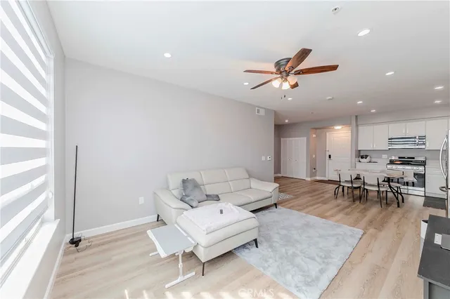 a kitchen with stainless steel appliances a refrigerator a stove a sink and white cabinets with wooden floor