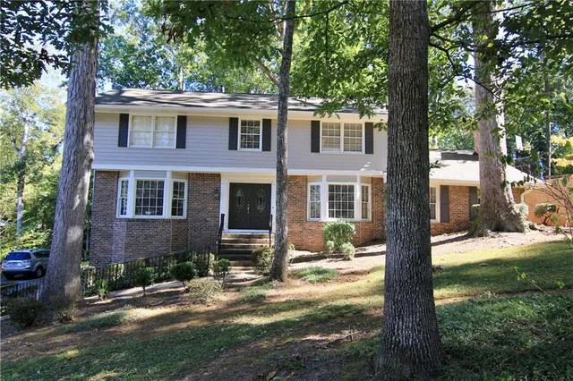 a view of a brick house with a yard and large tree