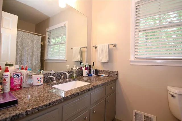 a bathroom with a granite countertop sink a large mirror and a window