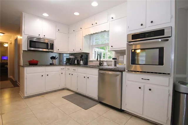 a kitchen with stainless steel appliances granite countertop a sink a stove a microwave and cabinets