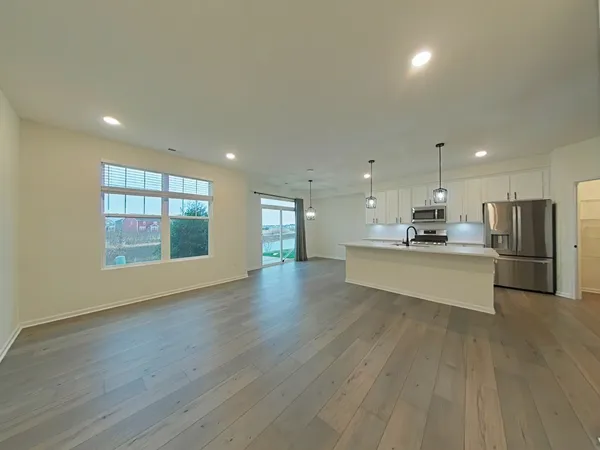 a large kitchen with stainless steel appliances granite countertop a large counter top and a wooden floor