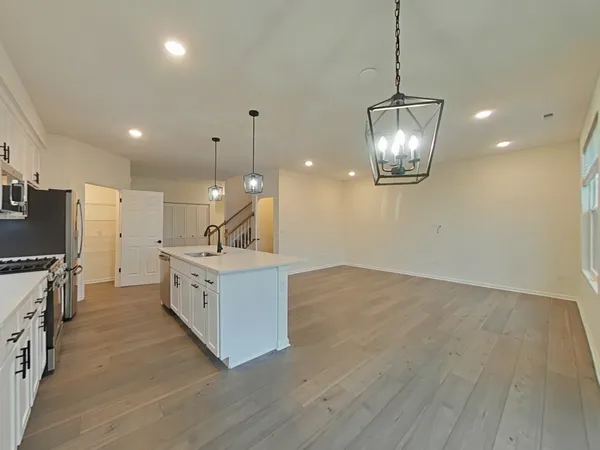 a open kitchen with stove a refrigerator and a wooden floor