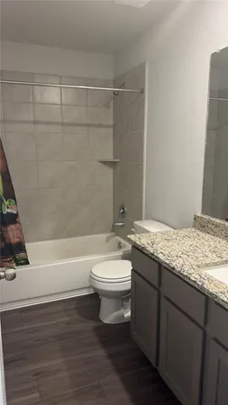 a bathroom with a granite countertop sink and a toilet
