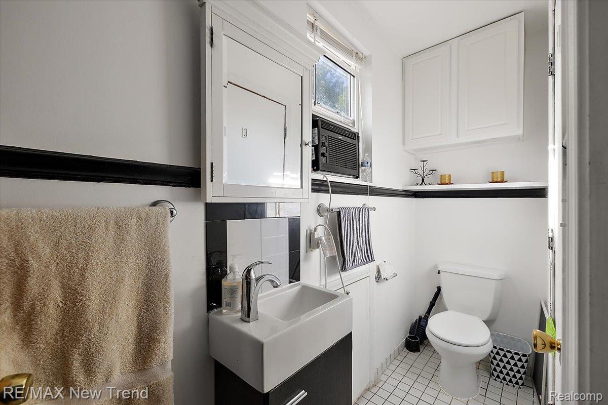 1450 Lenox Road Bloomfield Hills, MI 48304 - Photo 61 of 79 White subway tile, wall-mounted sink, white wall cabinets, white toilet, and tile flooring