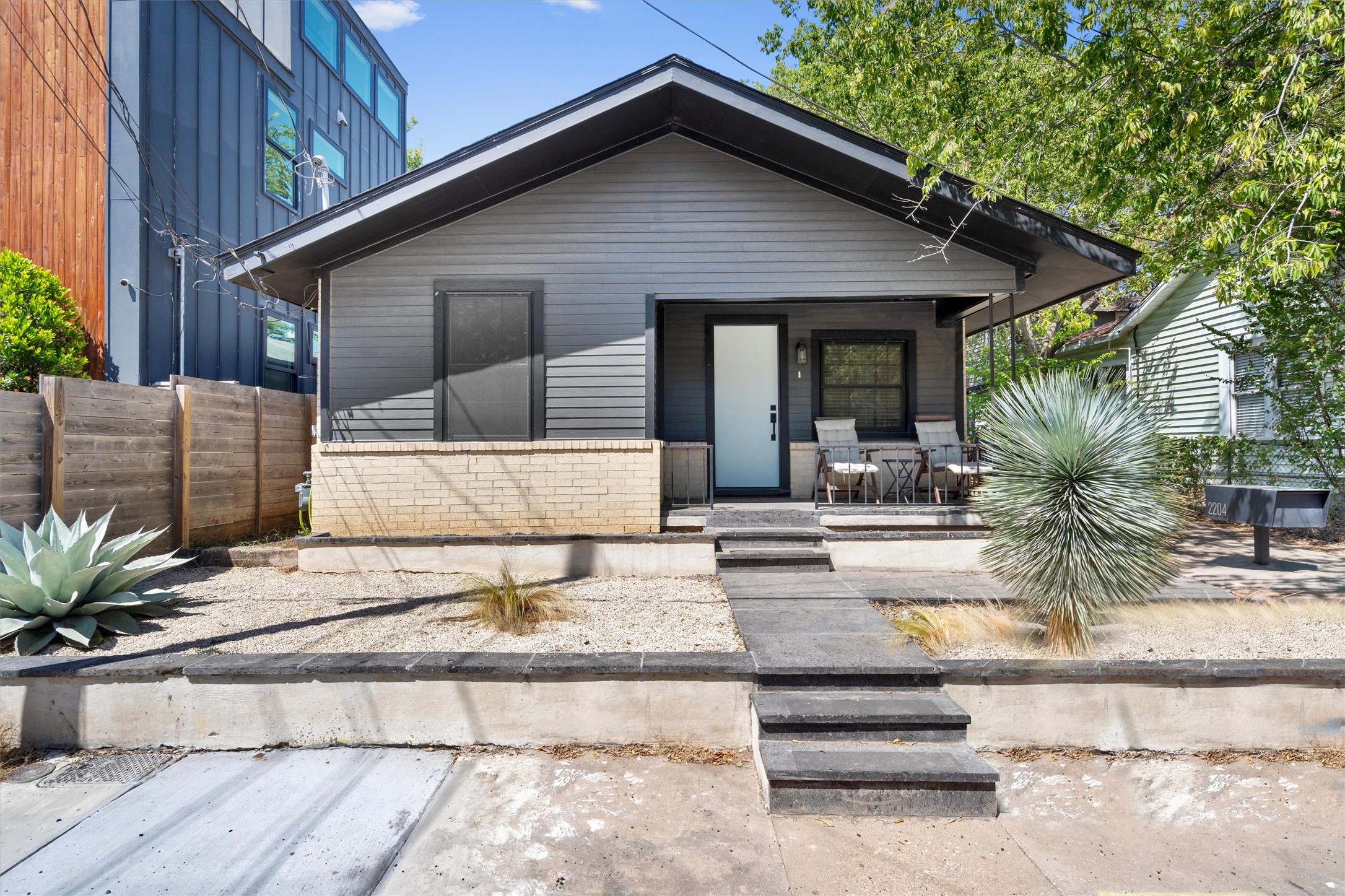 An inviting front porch welcomes guests to this modern single-story residence with xeriscaped front yard landscaping.