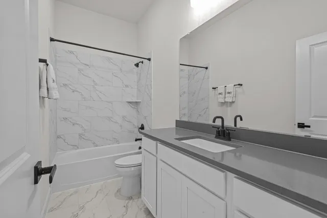 a bathroom with a granite countertop sink a toilet and a bathtub