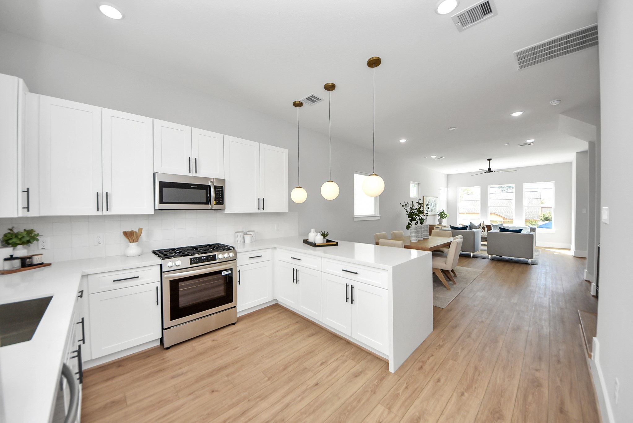 4812 Cochran Street Houston, TX 77009 - Photo 22 of 48 a large white kitchen with a stove top oven a chimney wooden floor and cabinets