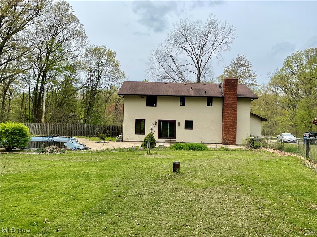1995 Claus Road Vermilion, OH 44089 - Photo 2 of 21 Rear view of house featuring a fenced backyard, stucco siding, a chimney, a fenced in pool, and a yard