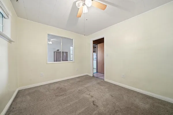 an empty room with a ceiling fan and window