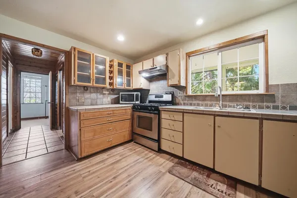a kitchen with stainless steel appliances granite countertop a stove a sink and white cabinets with wooden floor