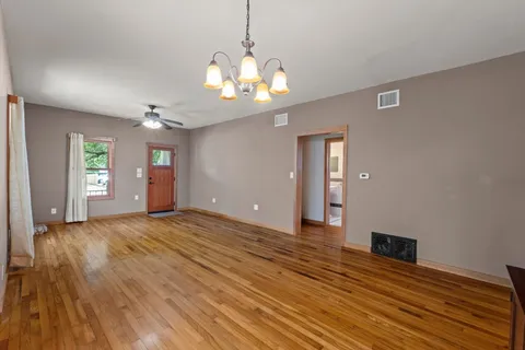 a view of an empty room with window and wooden floor