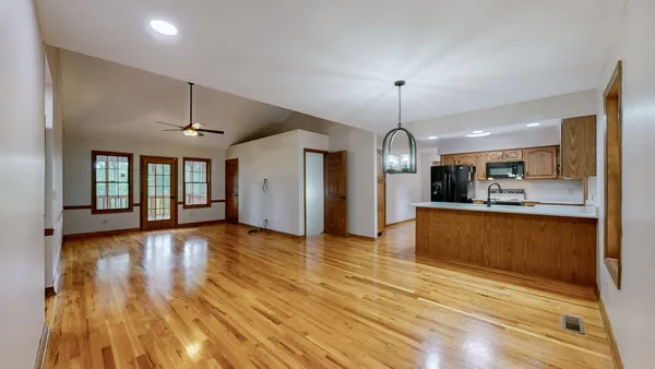a view of an empty room with a window and wooden floor
