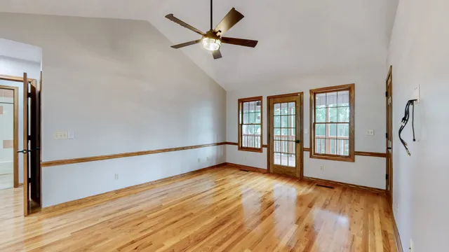 a view of an empty room with a window and wooden floor