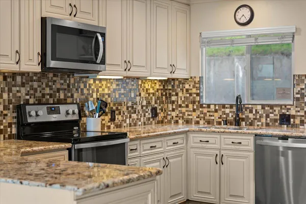 a kitchen with granite countertop a stove top oven microwave and cabinets