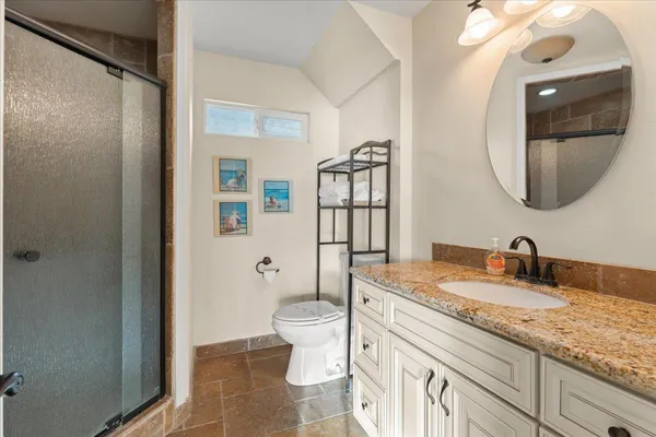 a bathroom with a granite countertop sink mirror vanity and toilet