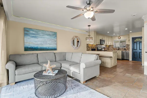 a living room with furniture kitchen view and a chandelier